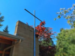 Image of Cross on a building with fall leafy background.